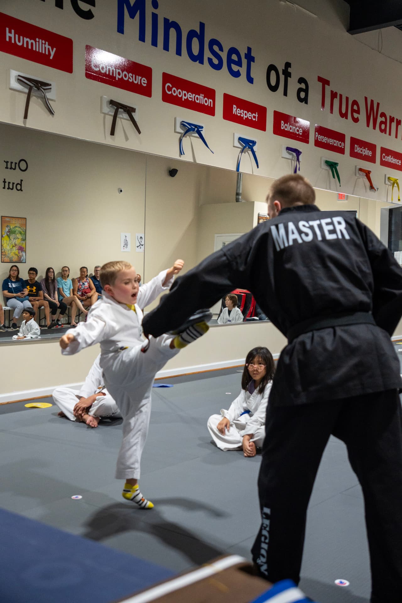Young Juniors student kicking a pad held by the instructor