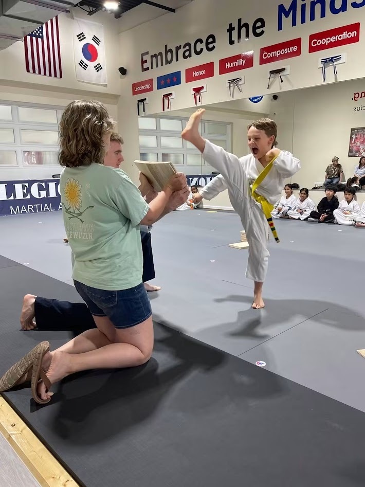 Juniors student breaking a board while family watches